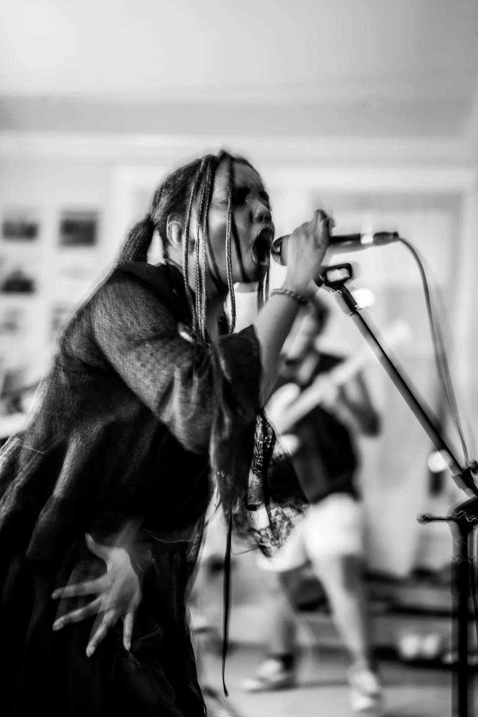 Singer leaning into the mic, in black and white