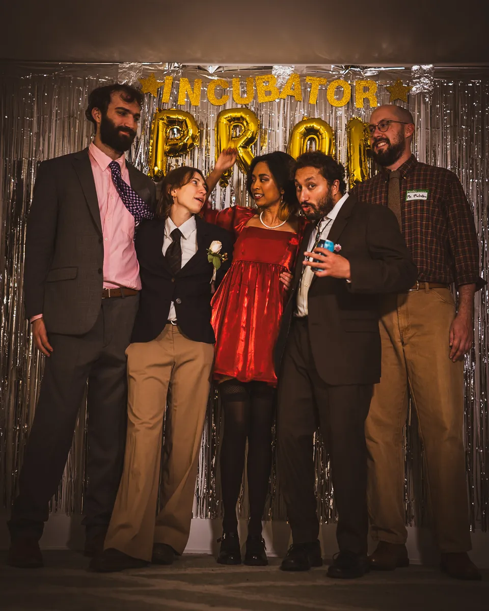 Friends in suits and a red dress posing at the prom backdrop