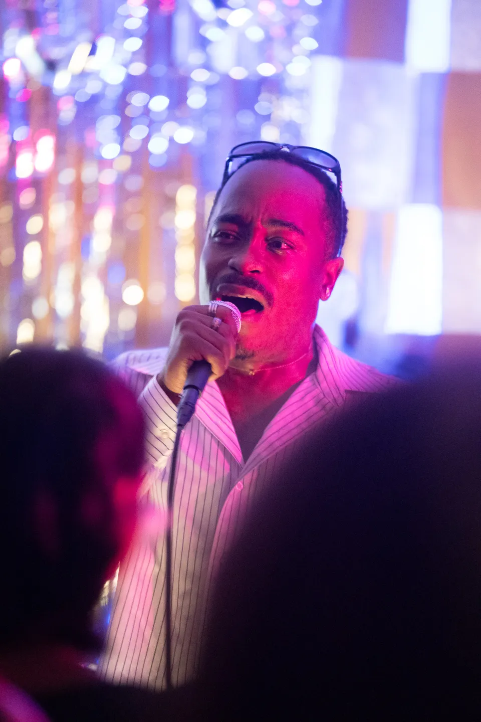 Singer belting into a microphone under colored lights