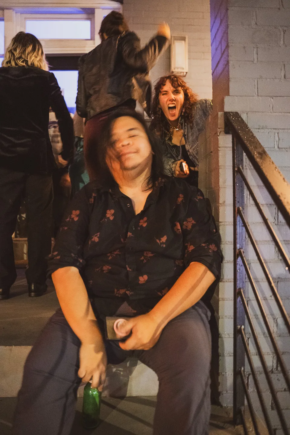 Partygoer slumped happily on the stairs as others dance past