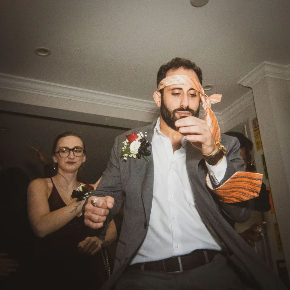 Man in a suit with a boutonniere dancing with a necktie around his head