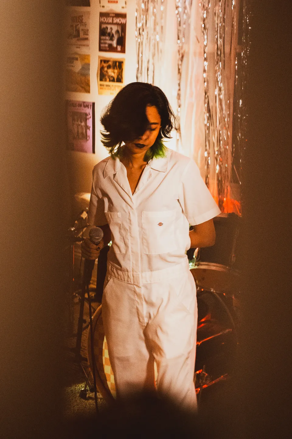 Performer in a white jumpsuit against tinsel