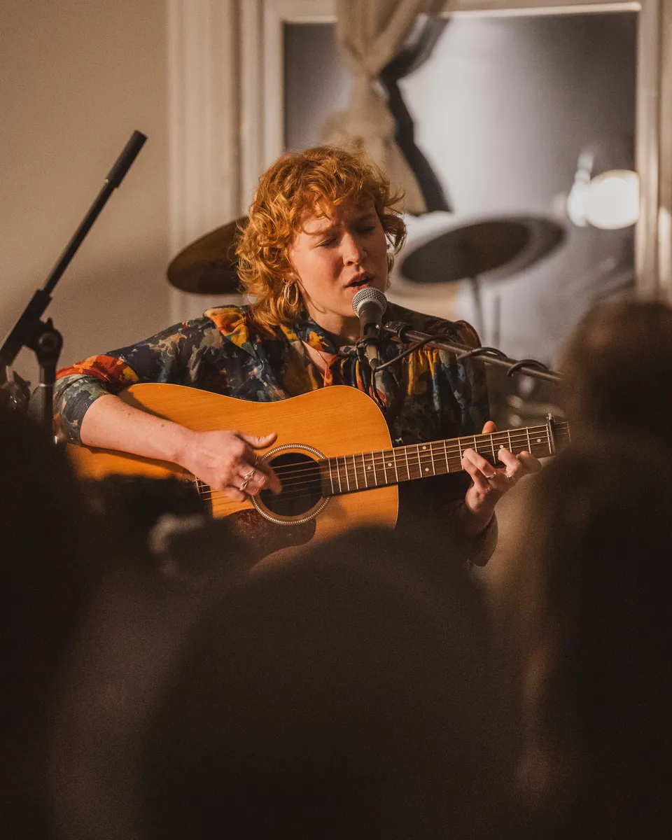 Singer with an acoustic guitar in a living room