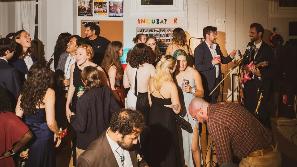 A packed living room under the Incubator sign