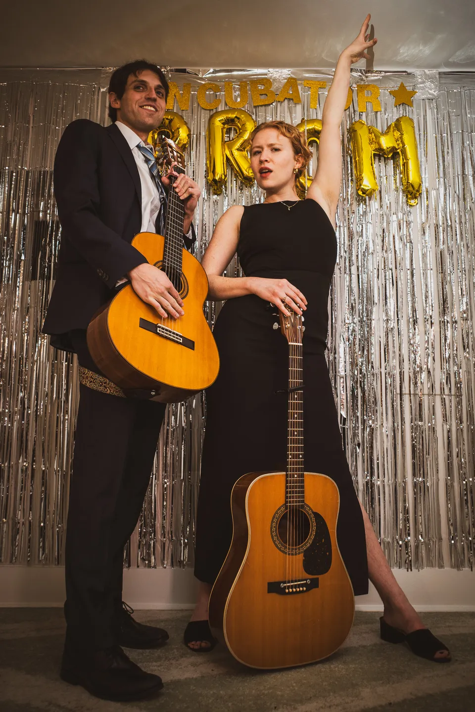 Two musicians with guitars posing at the prom backdrop